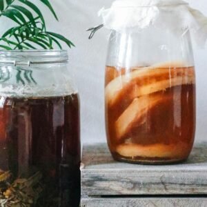 Close-up of kombucha brewing in jars with a rustic setting, showcasing natural fermentation process.