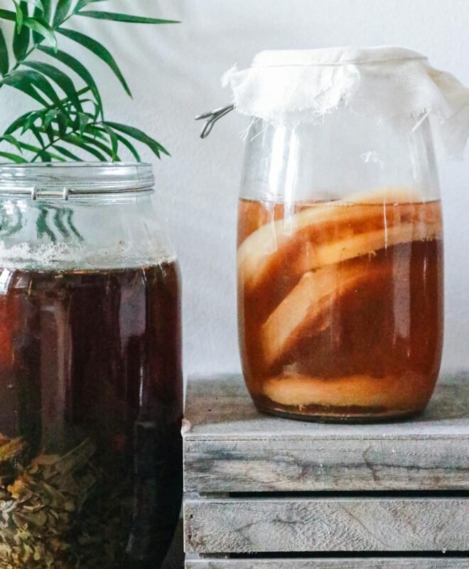 Close-up of kombucha brewing in jars with a rustic setting, showcasing natural fermentation process.