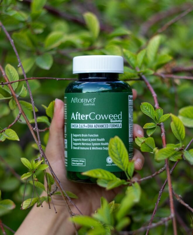 Hand holding a supplement bottle amidst vibrant green foliage outdoors.